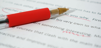 A manuscript and red pen, with suggested edits marked on the text.